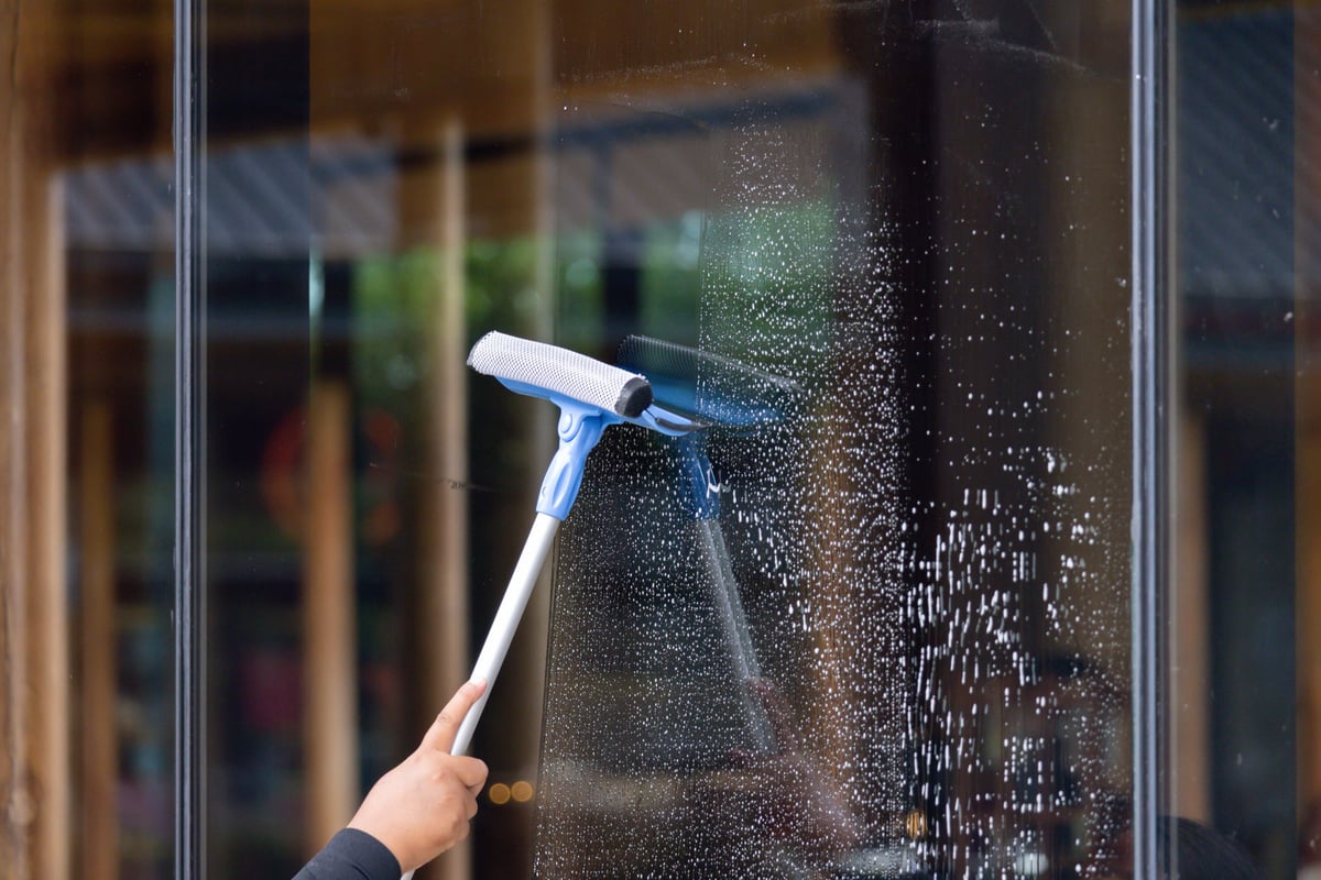 Technician cleaning an exterior home window with a squeegee