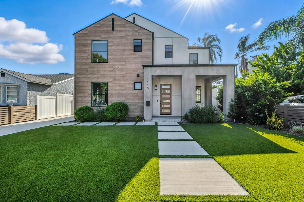 Vinings-style modern home with a manicured lawn and lush greenery